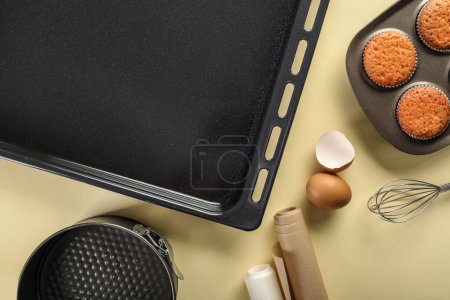 Photo for Baking trays with muffins, eggs and utensils on beige background - Royalty Free Image