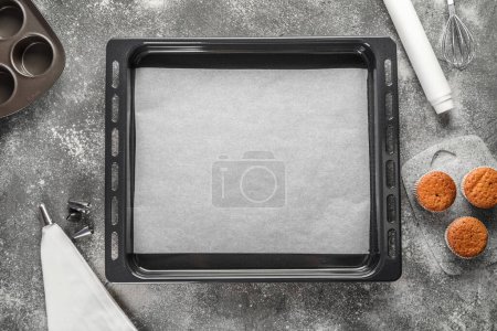 Photo for Baking trays with muffins and utensils on grunge background - Royalty Free Image