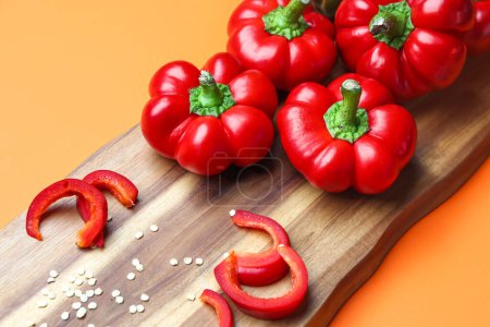 Foto de Wooden board of fresh bell peppers on color background, closeup - Imagen libre de derechos