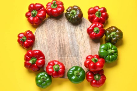 Foto de Composition with fresh bell peppers and wooden plate on yellow background - Imagen libre de derechos