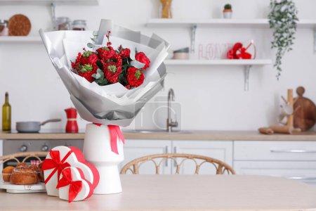 Téléchargez les photos : Vase with flowers, pastries and gifts for Valentine's Day on dining table in kitchen - en image libre de droit