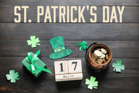 Photo for Leprechaun's pot with golden coins, gift and calendar with date of St. Patrick's Day on dark wooden background - Royalty Free Image