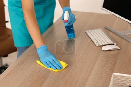 Photo for Female janitor cleaning desk in office, closeup - Royalty Free Image