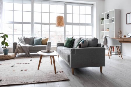 Foto de Interior of modern living room with grey sofas, window and shelving unit - Imagen libre de derechos