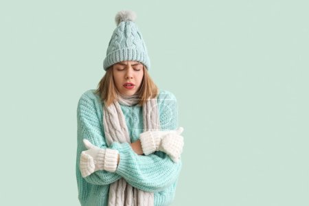 Téléchargez les photos : Frozen young woman in winter clothes on green background - en image libre de droit
