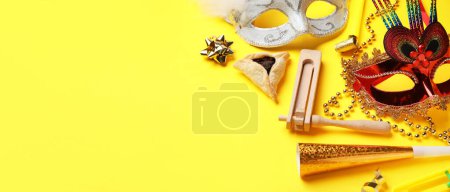 Foto de Hamantaschen cookie, carnival masks and noisemakers for Purim holiday on yellow background with space for text - Imagen libre de derechos
