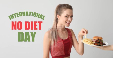 Photo for Sporty woman eating unhealthy food on light background. International No Diet Day - Royalty Free Image