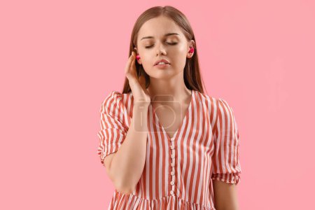 Téléchargez les photos : Young woman with ear plugs on pink background - en image libre de droit