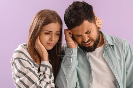 Téléchargez les photos : Young couple suffering from loud noise on lilac background, closeup - en image libre de droit