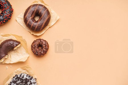 Téléchargez les photos : Parchments with different delicious donuts on beige background - en image libre de droit