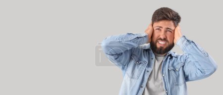 Photo for Young man suffering from loud noise on grey background with space for text - Royalty Free Image