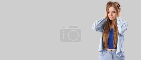 Photo for Young woman suffering from loud noise on grey background with space for text - Royalty Free Image