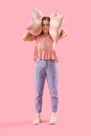 Téléchargez les photos : Young woman with pillows suffering from loud noise on pink background - en image libre de droit