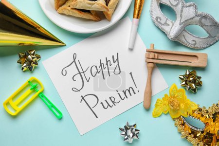 Foto de Card with text HAPPY PURIM, Hamantaschen cookies, carnival masks and rattles for Purim holiday on green background, closeup - Imagen libre de derechos