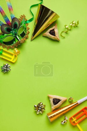 Foto de Frame made of Hamantaschen cookies, carnival mask and rattles for Purim holiday on green background - Imagen libre de derechos