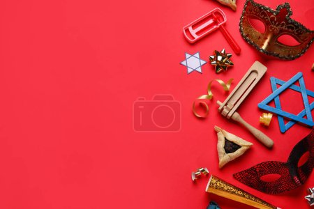 Foto de Hamantaschen cookie, carnival masks and rattles for Purim holiday on red background - Imagen libre de derechos