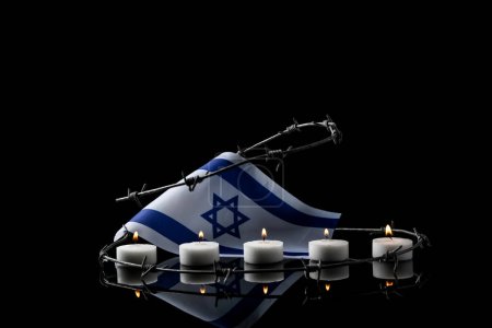 Foto de Burning candles, flag of Israel and barbed wire on dark background. International Holocaust Remembrance Day - Imagen libre de derechos