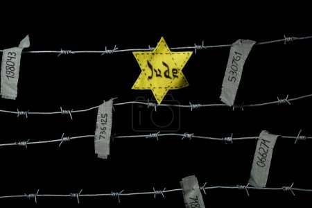 Téléchargez les photos : Barbed wire with Jewish badge and prisoner numbers on dark background. International Holocaust Remembrance Day - en image libre de droit