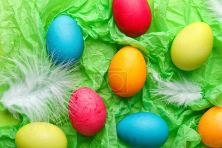 Téléchargez les photos : Painted Easter eggs and feathers on color crumpled paper, closeup - en image libre de droit