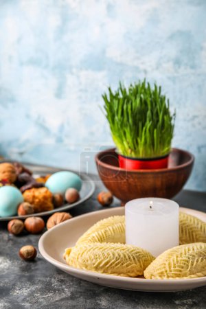 Teller mit brennender Kerze und Schekarbura auf dem Tisch, Nahaufnahme. Novruz Bayram-Feier
