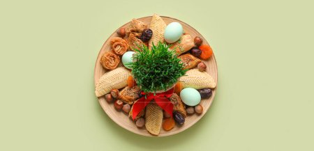 Teller mit Süßigkeiten, Eiern und Weizengras auf grünem Hintergrund. Novruz Bayram-Feier