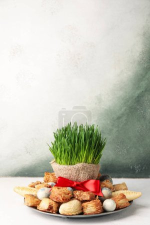 Teller mit Leckereien, Eiern und Gras auf dem Tisch neben der Grunge-Wand. Novruz Bayram-Feier
