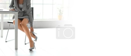 Photo for Young businesswoman taking off her shoes in office. Banner for design - Royalty Free Image