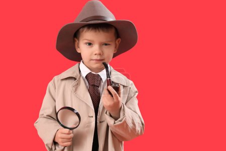 Foto de Cute little detective with magnifier and smoking pipe on red background - Imagen libre de derechos