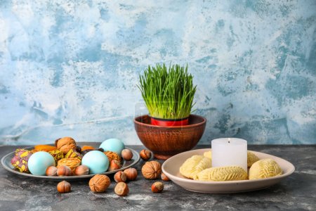 Téléchargez les photos : Assiettes avec friandises, œufs et herbe sur la table près du mur de grunge. Novruz Bayram célébration - en image libre de droit