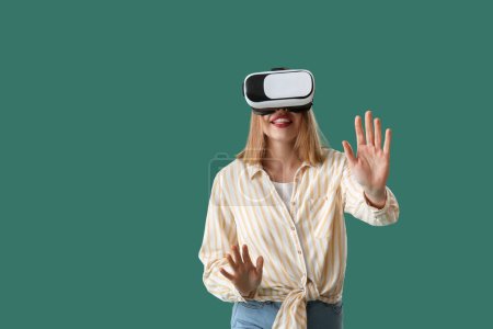 Photo for Pretty young woman in VR glasses on green background - Royalty Free Image