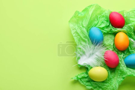 Téléchargez les photos : Crumpled paper with painted Easter eggs and feathers on color background - en image libre de droit