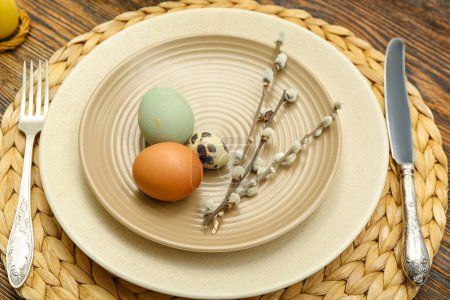 Table setting with Easter eggs and pussy willow branches on wicker mat, closeup