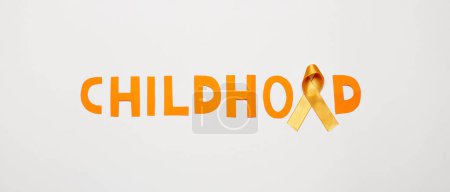 Téléchargez les photos : Golden ribbon and word CHILDHOOD on light background. Cancer awareness concept - en image libre de droit