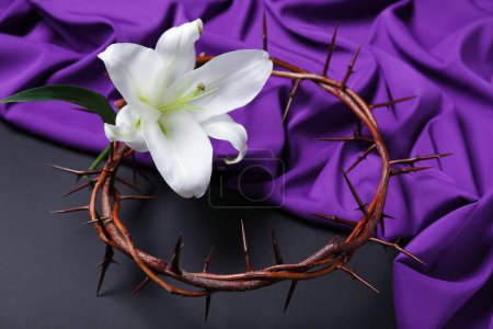 Téléchargez les photos : Crown of thorns with lily flower and purple fabric on dark background, closeup. Good Friday concept - en image libre de droit