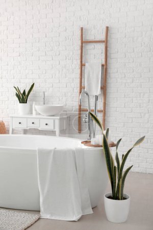 Photo pour Interior of light bathroom with bathtub, sink and ladder - image libre de droit