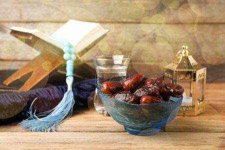 Photo for Bowl with dried dates, Quran book and fanous lamp on wooden background - Royalty Free Image