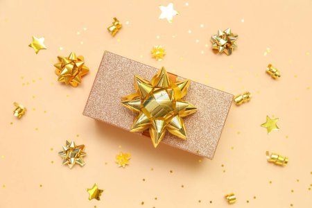 Téléchargez les photos : Coffret cadeau avec noeuds dorés et étoiles sur fond beige - en image libre de droit