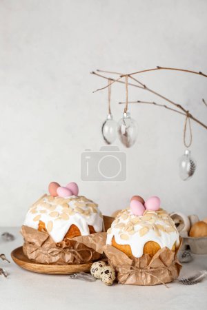 Foto de Pasteles de Pascua con huevos pintados y plumas en la mesa cerca de la pared blanca - Imagen libre de derechos
