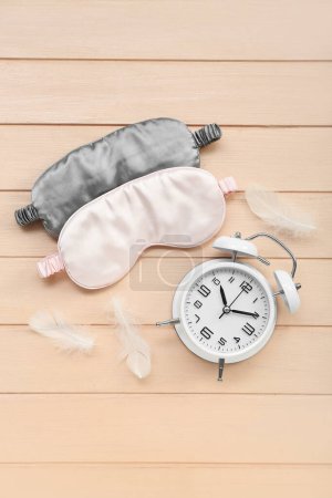 Photo for Sleeping masks, alarm clock and feathers on color wooden background. World Sleep Day concept - Royalty Free Image