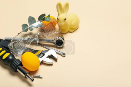 Téléchargez les photos : Work tools with Easter eggs and toy rabbit on beige background - en image libre de droit