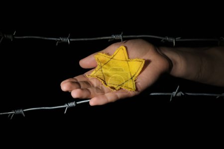 Frau mit gelbem Judenabzeichen und Stacheldraht auf dunklem Hintergrund. Internationaler Holocaust-Gedenktag