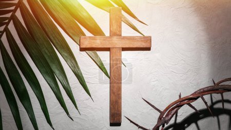Foto de Crown of thorns with wooden cross and palm leaf on light background. Good Friday concept - Imagen libre de derechos