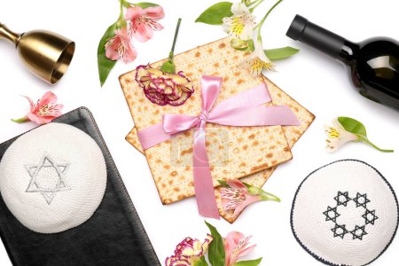 Foto de Composición con matza de pan plano, kippahs, flores de alstroemeria y botella de vino sobre fondo blanco - Imagen libre de derechos