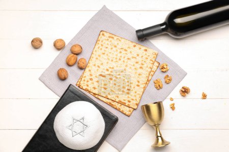 Composition with flatbread matza, walnuts, kippah, cup and bottle of wine on light wooden background