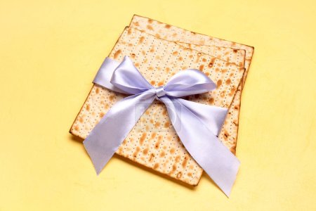 Jewish flatbread matza for Passover tied with ribbon on yellow background