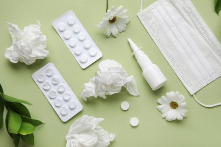 Foto de Gotas nasales con pastillas, flores, máscara médica y tejidos sobre fondo verde. Concepto de alergia estacional - Imagen libre de derechos