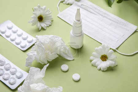 Photo for Nasal drops with pills, flowers, medical mask and tissues on green background, closeup. Seasonal allergy concept - Royalty Free Image