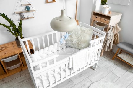Photo for Interior of light children's bedroom with baby crib and table - Royalty Free Image
