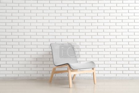 Foto de Modern grey armchair near white brick wall - Imagen libre de derechos