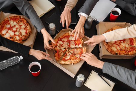 Photo for Group of business people taking tasty pizza from table in office, top view - Royalty Free Image